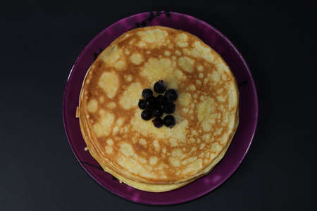 Delicious fried pancakes with frozen currants isolated on a black background. A great treat for Shrovetideの写真素材