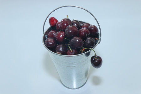 Cherries in a metal bucket on a white background close-upの写真素材