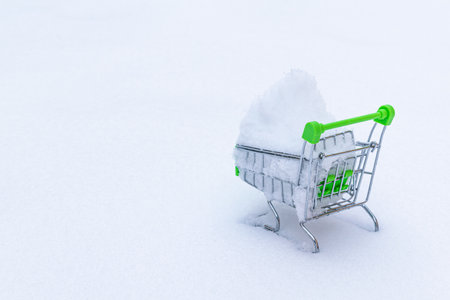 Green shopping cart with snow inside on a white background.の写真素材