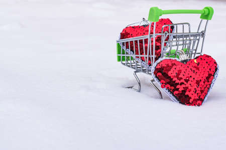 Two red hearts and a cart on the winter snow.