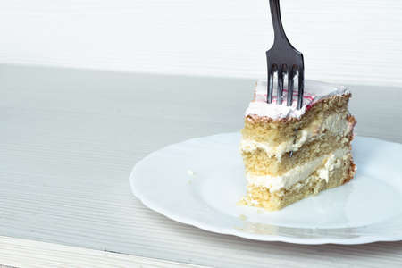 A fork cuts through a piece of vanilla cakeの写真素材