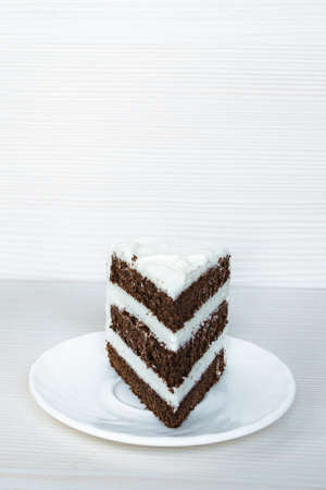 A chocolate sponge cake with butter cream is located in the middle. White background. Vertical photography.の写真素材