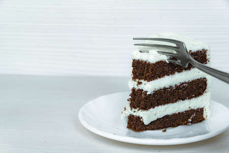 Fork and chocolate cream cake located on the right.の写真素材
