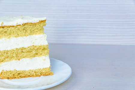A piece of vanilla bisquit cake with butter cream located on the left. White background. Close-up.の写真素材
