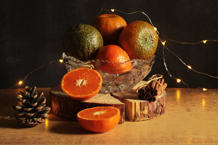 Christmas still life with tangerines and christmas lights on dark background