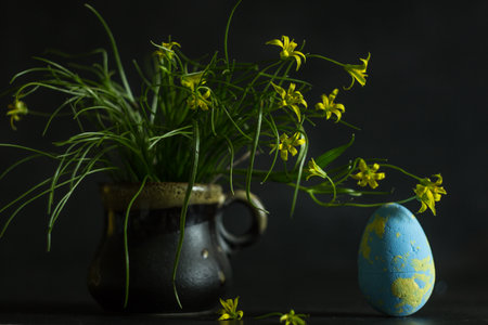 Easter eggs and spring flowers in a vase on a dark backgroundの写真素材