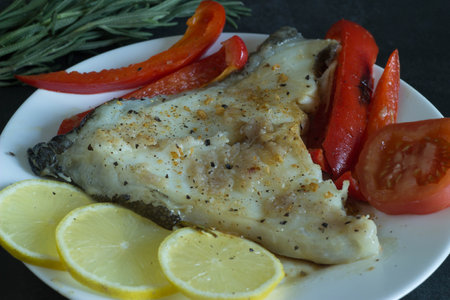 Fish fillet with tomatoes, lemon and rosemary on a plate