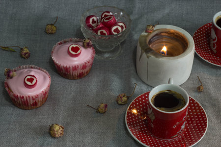 Cupcakes with red icing and a cup of coffee on a gray backgroundの写真素材