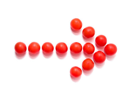 Arrow made of red cherry tomatoes on white backgroundの写真素材