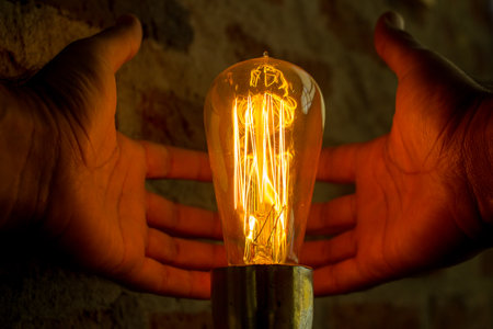 Hands holding a lightbulb in the form of a bulbの写真素材