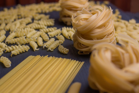 Different types of dry pasta on a dark background. Selective focus.の写真素材