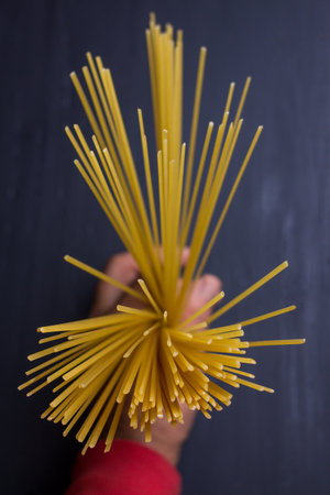 Closeup of a man holding a bunch of spaghetti on a black backgroundの写真素材