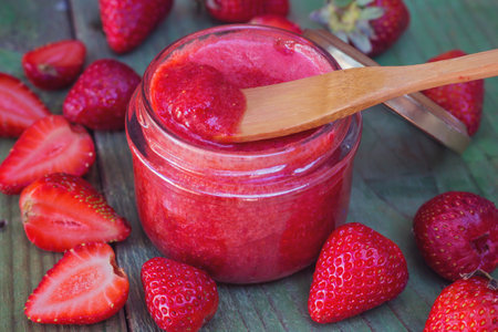 Strawberry jam in a jar and fresh strawberries on a wooden backgroundの写真素材