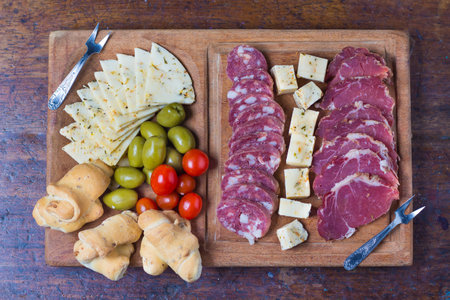 Spanish tapas on a wooden board with olives, cheese and crackersの写真素材
