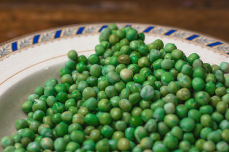 Green peas in a ceramic bowl on a wooden table. Selective focus.の写真素材