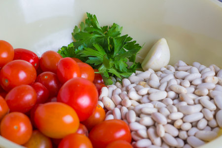 Cherry tomatoes and white beans in a bowl with parsley.の写真素材