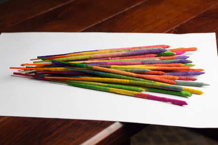 Colorful incense sticks on a white paper on a wooden tableの写真素材