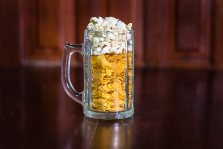 cornflakes and popcorn in a glass on a wooden background.の写真素材