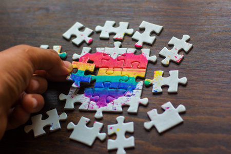 Colorful jigsaw puzzle pieces with the word pride on wooden backgroundの写真素材