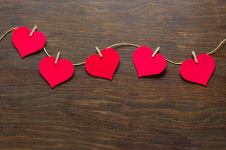Red paper hearts hanging on rope on wooden background. valentines day conceptの写真素材