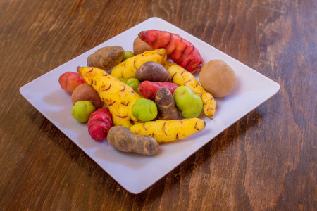 Assorted fresh fruits and vegetables on a white plate on a wooden tableの写真素材