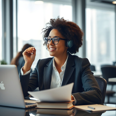 smiling african american businesswoman in headset working with papers in officeの素材