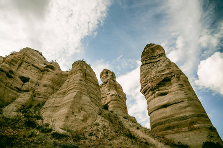 Dramatic rock formations reaching towards cloudy blue sky