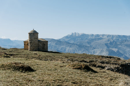 Ancient stone chapel or fortress on a hilltop with mountain ranges in the backgroundの写真素材
