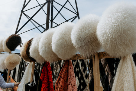 Winter hats with large pom-poms displayed at a market stallの写真素材