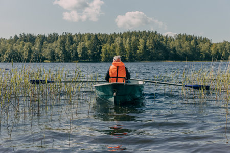 A small boat on a lake surrounded by reeds and forestの写真素材