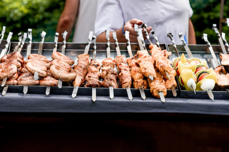 Meat kebabs on skewers cooking on the grill outsideの写真素材