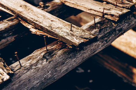 Old rusty nails sticking out of a wooden collapsed bridge, structural repair