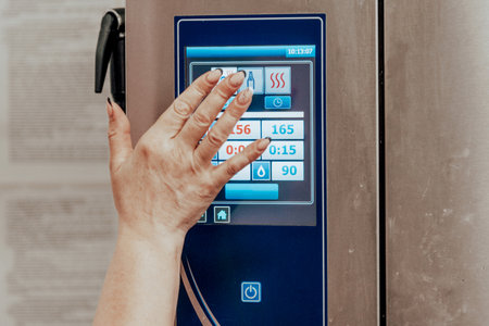 Utility worker in restaurant pressing buttons on refrigerator control panel, cook freezing food