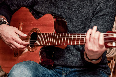 Close-up view of hands playing an acoustic guitar, showing musical performance technique