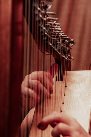A person plays the strings of a harp during a performance