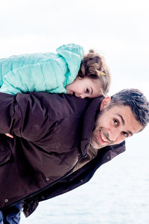 Family dad and daughter walking outside in autumn, man and girl in jackets fooling around and playingの写真素材