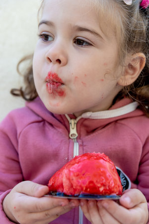 Cute funny little girl toddler child eating pink cake and laughing large portraitの写真素材