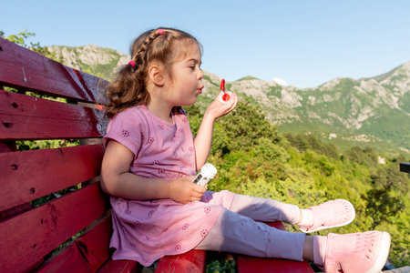 Cute funny little girl toddler child blowing soap bubbles in the park in summer outsideの写真素材