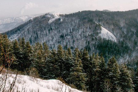 Landscape of snowy Siberia Krasnoyarsk mountains, peak range in haze winterの写真素材
