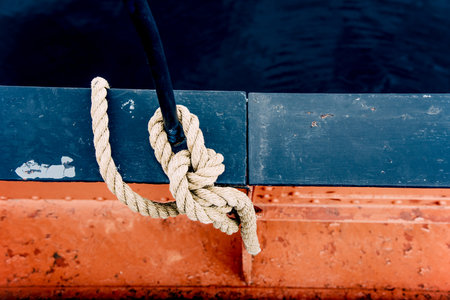 Close-up of mooring rope with knotted end tied around cleat on pier equipment sailboat