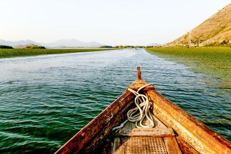 Wooden boat yacht sailing on the water of Skadar Lake in Montenegro, summer landscape on sunny day