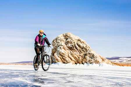 Woman cyclist tourist riding bicycle on the ice of Lake Baikal, Siberia, Russiaの写真素材