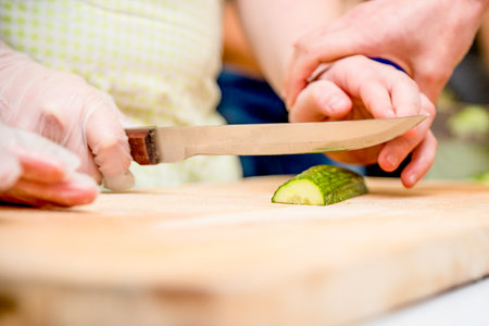 Chef in restaurant in kitchen preparing vegetable salad, close-up hands cutting tomato and cucumber on cutting boardの写真素材