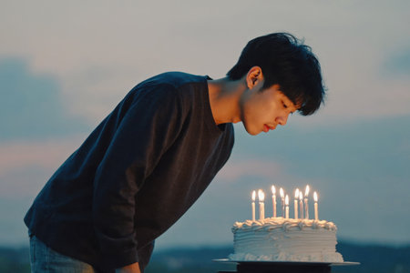 AI Generative Young man blowing out candles on cake, happy birthday celebrationの素材