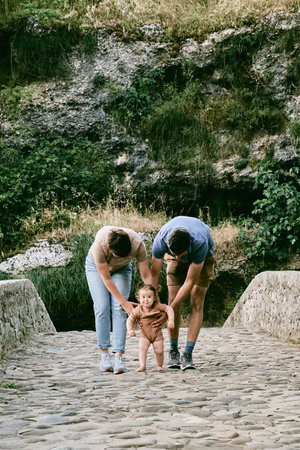Family mom, dad and daughter walking, woman and man teach little girlの写真素材