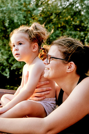 Portrait of family mother and daughter looking into the distance, woman hugging toddler girlの写真素材
