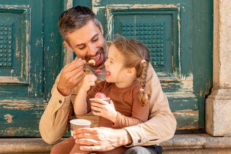 Family man and toddler girl eat ice cream, dad and daughter taste cold fruit dessertの写真素材