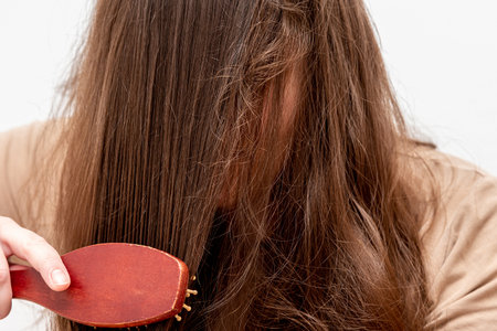 Young woman combining long dark hair with massage comb, daily care routine morningの写真素材