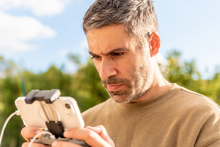 Man drone operator controls the UAV remotely from the control remote panel, photography and videography shooting from the skyの写真素材