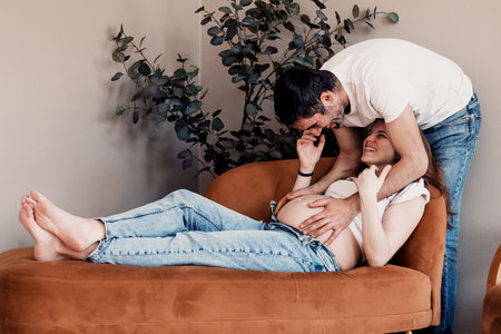 Married couple man and pregnant woman with big belly posing at photo shoot for expectant parents